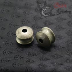 Close-up top side angle view of silver ear plug from Burma worn by Yinbao Karen, showing detailed craftsmanship and patina