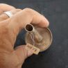 Antique Pa-O silver ear plug held in hand, side view