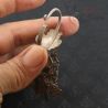 Macro close-up of floral motif and spiral charms on Yao earring hand held