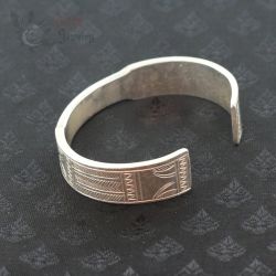 Contemporary Lahu silver bangle photographed from top side angle on dark textile