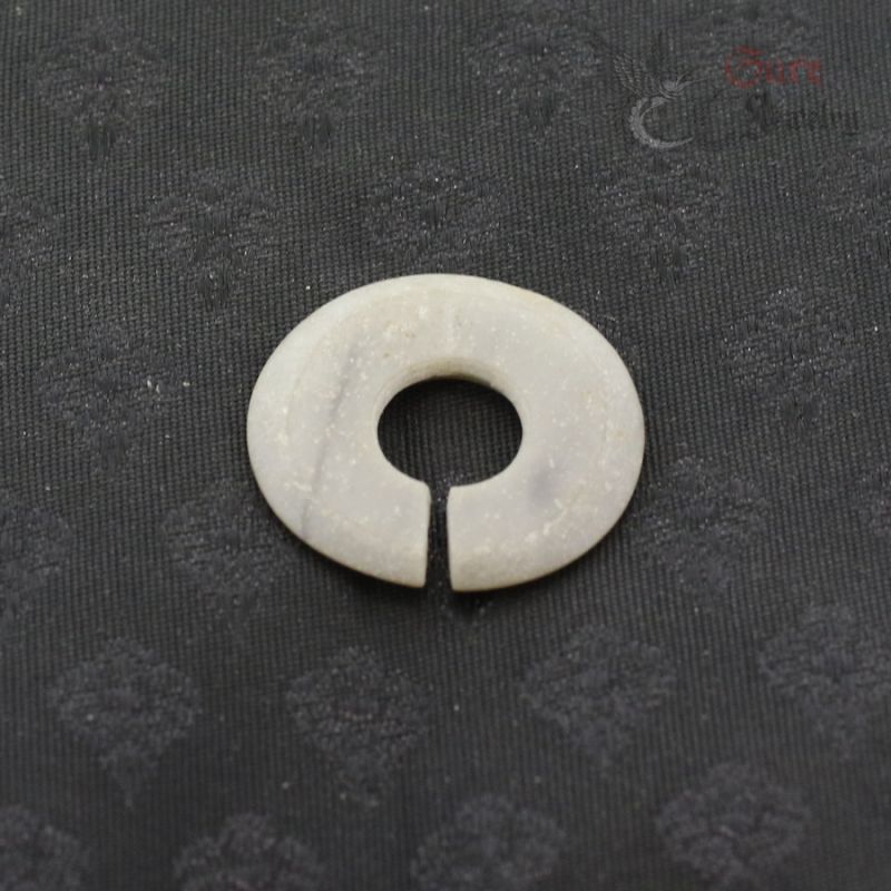 Ancient style jade like stone ear ornament slit ring top view on dark textile
