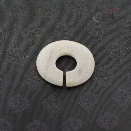 Ancient style jade like stone ear ornament slit ring top view on dark textile
